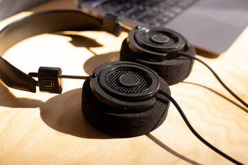 Black music headphone with laptop computer on wooden table. Top view background for a list of music on a sunny autumn day. Listen to podcasts
