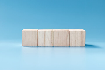Four blank wooden blocks on blue background.