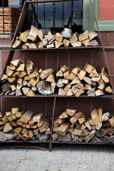 Chopped firewood stacked against the wall of the house for heating in the winter. A woodpile with a blank and stacked firewood from chopped dry wood for kindling and heating the house.