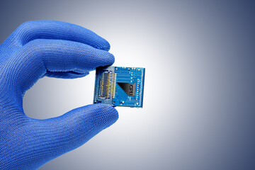 hand holds a cpu against the grey blue background.  Concept of production or repair electronic...