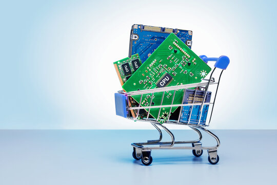 electronics chips, elements and board in  shopping cart on blue background with copy space.