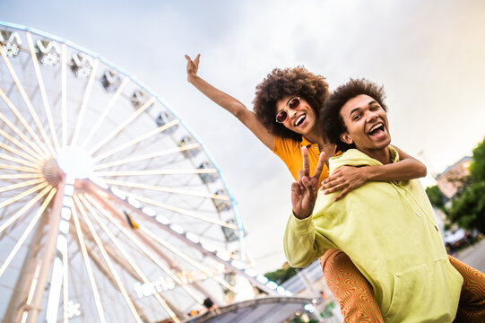 Multiracial young couple of lovers dating at theferry wheel in the amusement park - People with mixed races having fun outdoors in the city- Friendship, releationship and lifestyle concepts