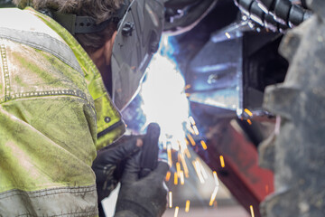 Welder is welding metal part of a forest machine.