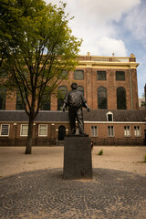 statue of the dokwerker, dock worker or docker that is a monument to Jonas Daniël Meijerplein in Amsterdam in memory of the February strike of 1941 supporting jews against the nazis. Synagogue behind. - 564207447