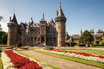 outside of Kasteel De Haar Dutch medieval castle with floral garden on sunny summer day. Flowers match colour of Utrecht Netherlands where historic building with European architecture is located
