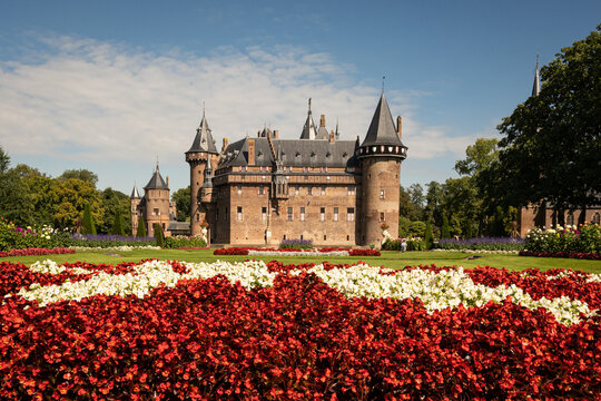outside of Kasteel De Haar Dutch medieval castle with floral garden on sunny summer day. Flowers match colour of Utrecht Netherlands where historic building with European architecture is located
