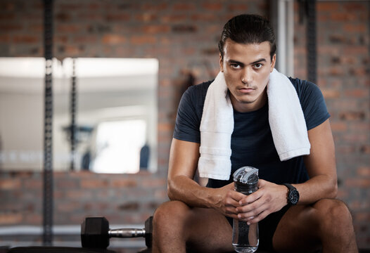 Portrait, man and water bottle in gym for break, rest and energy to focus after exercise with towel. Sports man, bodybuilder and athlete relax after workout, training and wellness in fitness club