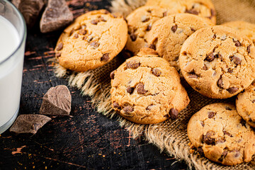 Pile of homemade cookies with pieces of milk chocolate on the table. 