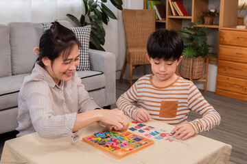 Asian happy single mother and son playing alphabet games with plastic toys, mom helping child learn foreign language for improve mental health and memory. family spending time together in holiday.