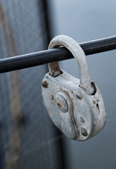 Ein altes Vorhängeschloss, als Liebesschloss, Liebesbeweis an einem Metallgitter befestigt.