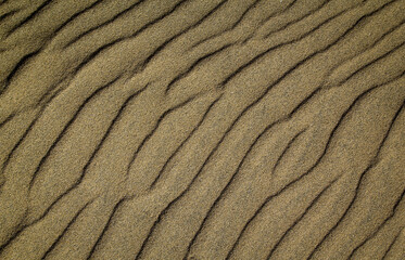 Eine durch Wind und Wellen entstandene Sandtextur am Strand.
