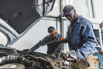 Fototapeta na wymiar Skilled mechanics repairing a car engine using tools in a modern auto repair shop. High-quality photo