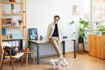Trendy male designer with dog in creative studio