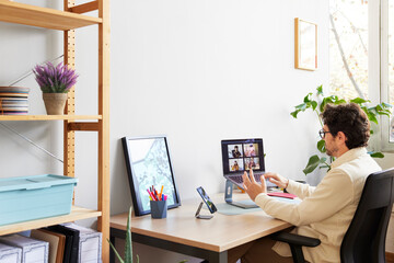 Focused designer having meeting with partners on laptop