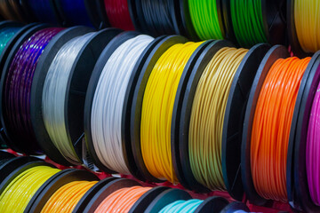 Many multi-colored spools of thread of filament for printing 3d printer. Material coils for printing 3D printer. Spools of 3D printing motley different colors filament. ABS wire plastic for 3d printer