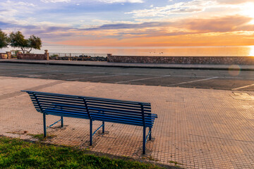 metallic bench on sea embarkment with asphalt road and beautiful seashore landscape with amazing cloudy sky
