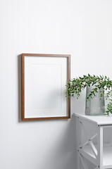 Fototapeta na wymiar Wooden picture frame mockup on white wall with botanical decor, blank mockup with copy space