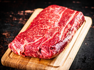 A piece of fresh raw beef on a cutting board. 