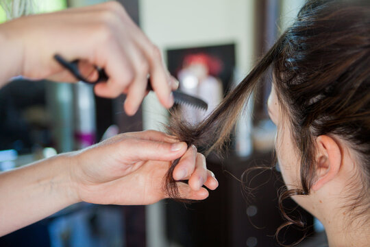 At a hair dresser, salon, detail of hands holding a comb and finishing a woman´´ s hair style. No face visible. Photo of a professional at work. 