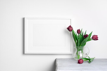 Landscape picture frame mockup on white wall with fresh tulips flowers