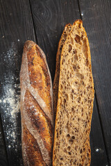 Crispy homemade baguette with wheat flour on a black rustic table