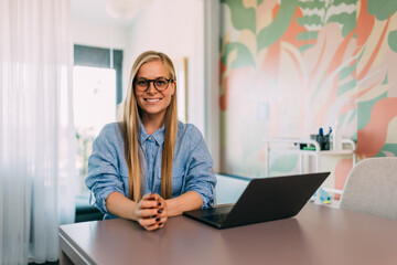 Portrait of a smiling woman, posing for the camera while being at the office.