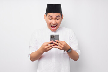 Surprised young Asian Muslim man using a mobile phone and reacting to online news isolated on white background. People religious Islam lifestyle concept. celebration Ramadan and ied Mubarak
