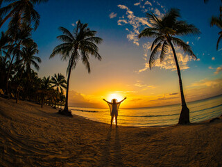 Woman standing on sunny, tropical beach at daybreak
