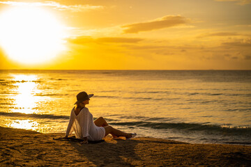 Fototapeta na wymiar Woman on sunny, tropical beach at daybreak 