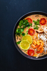 Tom Yum - Thai soup with prawns, shiitake mushrooms and noodles on wooden table

