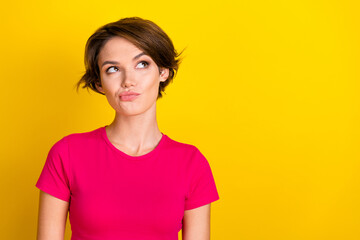 Fototapeta premium Photo of adorable doubtful lady wear pink t-shirt looking empty space isolated yellow color background