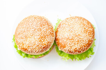 Two sandwiches with sesame rolls on a white plate