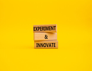 Experiment and innovate symbol. Concept words Experiment and innovate on wooden blocks. Beautiful yellow background. Business and Experiment and innovate concept. Copy space.