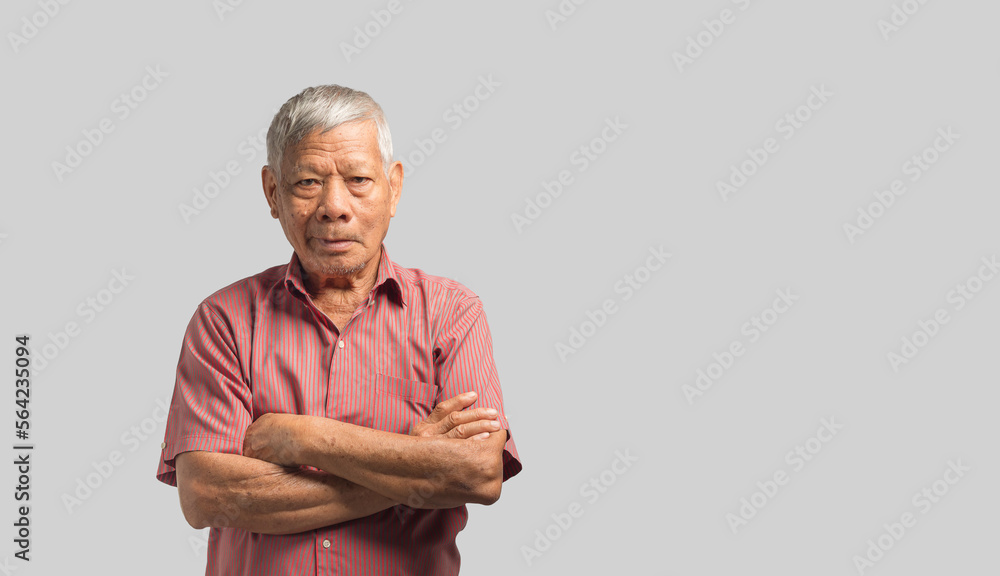 Poster senior man looking at the camera with a smile and arms crossed while standing on a gray background