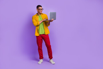 Full size portrait of positive smart man use wireless netbook coworking empty space isolated on purple color background
