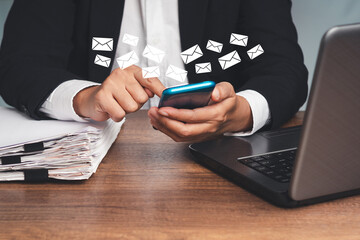 Businesswoman using a smartphone receives a new message with email icons while sitting at the table