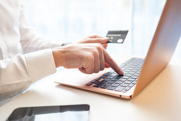 Purchases via the Internet and payment for services buy credit card. Hands type text and enter data on the laptop keyboard. An office worker checks his email while sitting at his desk