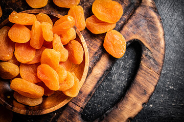 Dried apricots in a plate on a cutting board. 