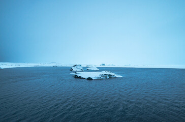 Iceberg formations floating in Jokulsarlon Lagoon on a cloudy blue-gray day with low visibility...