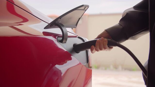 Kyiv, Ukraine. April, 2021. Rapid charging station used for red Tesla EV. Driver plugs in fast charger to her electric vehicle. High quality 4k footage
