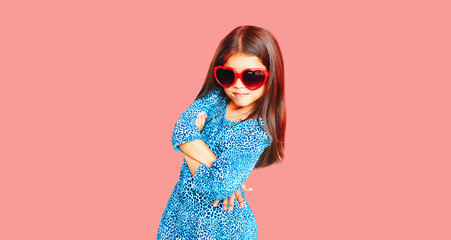 Portrait of beautiful little girl child wearing blue dress on pink background