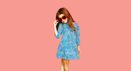 Portrait of beautiful little girl child wearing blue dress on pink background