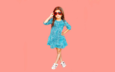 Portrait of beautiful little girl child wearing blue dress on pink background
