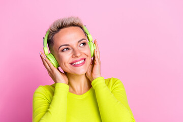 Portrait of gorgeous positive girl beaming smile arms touch headphones look empty space isolated on pink color background