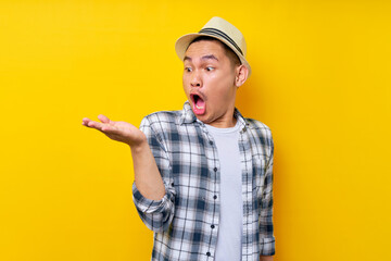 Surprised Asian ethnicity young man 20s wearing casual clothes hat looking palm, imagine the...