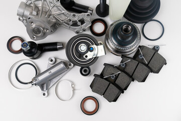 Lot of auto parts lie on white background. Engine and suspension parts, swivel knuckle, joint and...