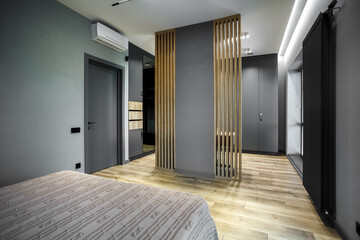 Modern luxury bedroom in loft style with dark and grey style. Dark headboard and wooden floor with wall panel