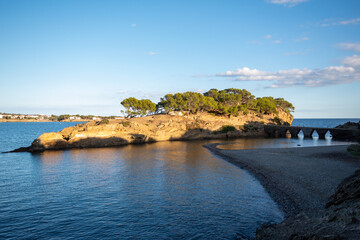 Puente hacia una isla en el pueblo de la Costa Brava de Cadaqu&eacute;s rodeada del azul mar Mediterr&aacute;neo con el sol ba&ntilde;&aacute;ndolo todo.