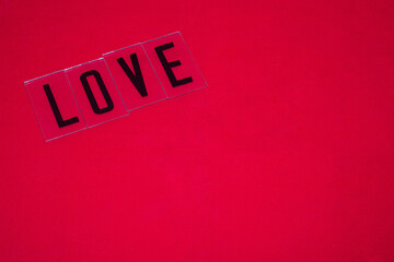 Palabra LOVE escrita con letras negras en mayuscula sobre un fondo rojo por el día de los enamorados.