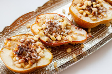 Baked pears with nuts, honey and cinnamon on silver tray